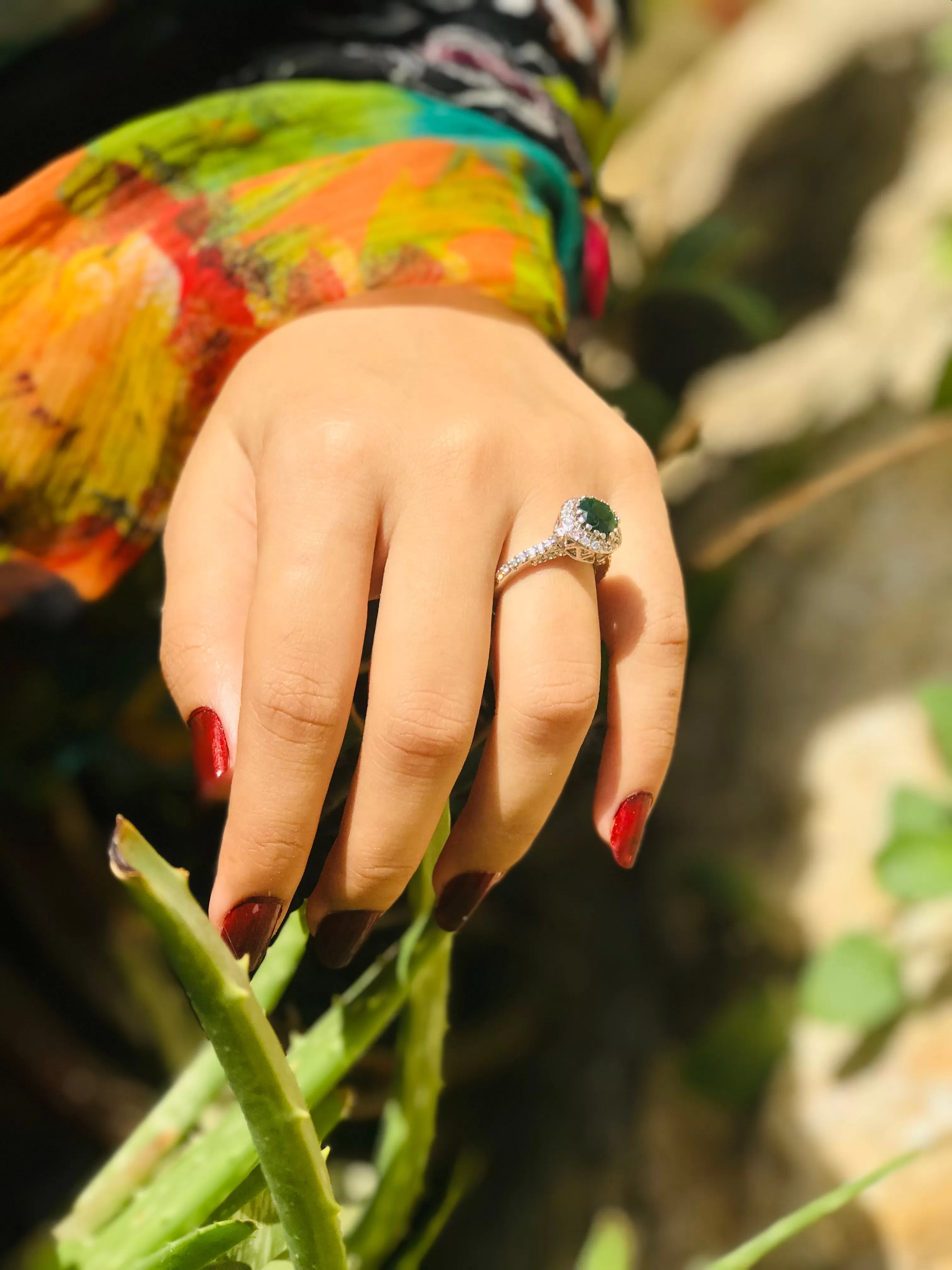 An alluring dark green emerald stone surrounded by small shiny diamonds (925 Sterling Silver)